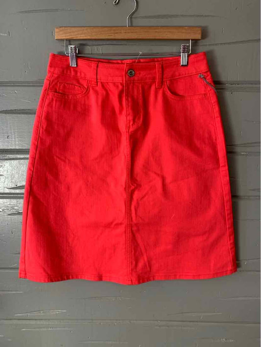 Bright pink denim skirt with front pockets and button closure, size 4 hanging on wooden hanger.
