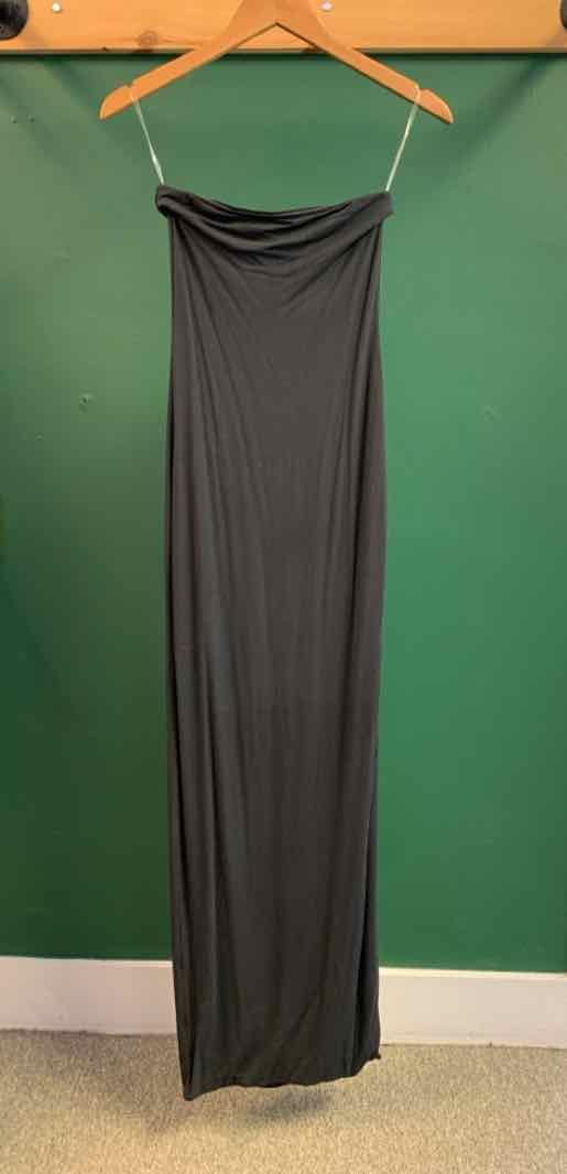 Black strapless maxi dress with straight neckline hanging on wooden hanger against green wall.
