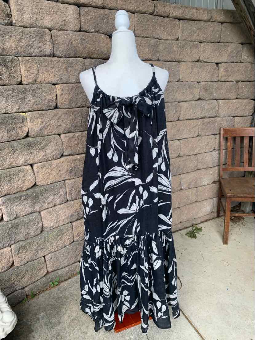 Black floral midi dress with white leaf pattern, thin spaghetti straps, and ruffled hem.