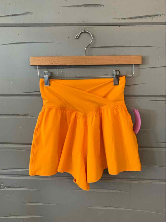 Bright orange high-waist shorts with a flared, skirt-like design and a wide waistband.