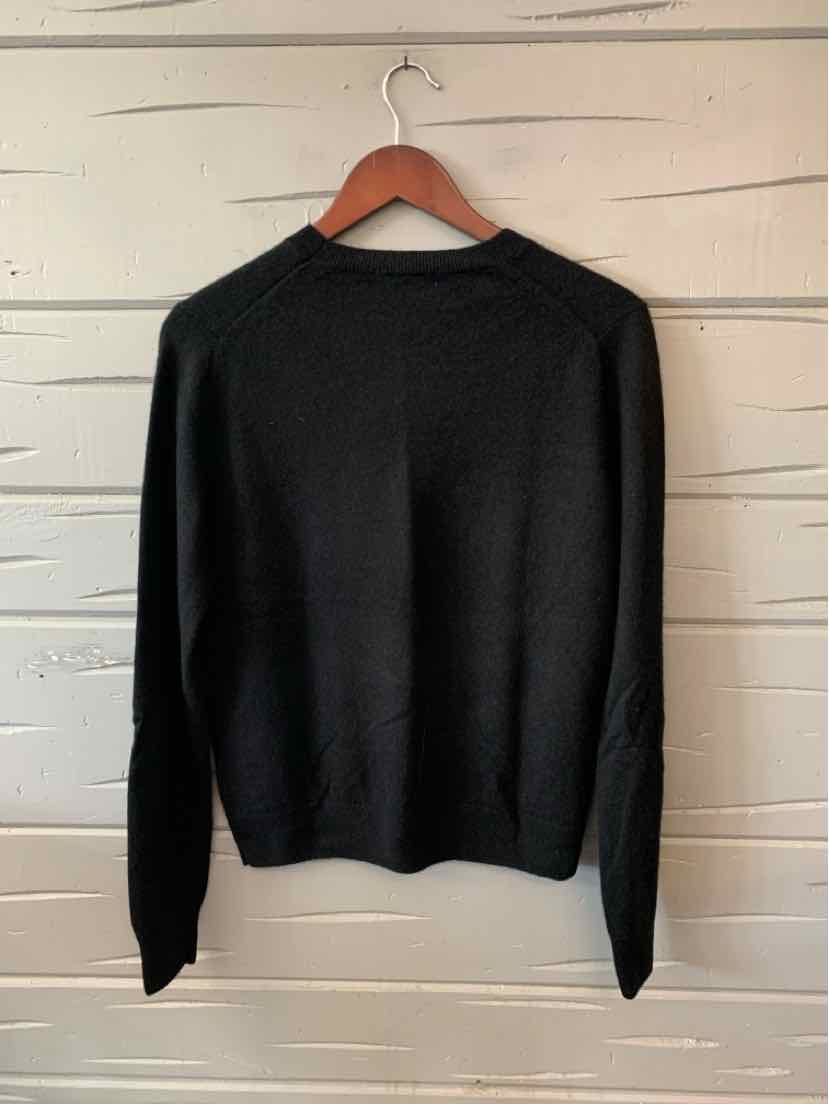 Black long-sleeve crewneck sweater in medium size with a smooth knit texture, hanging on wooden hanger.