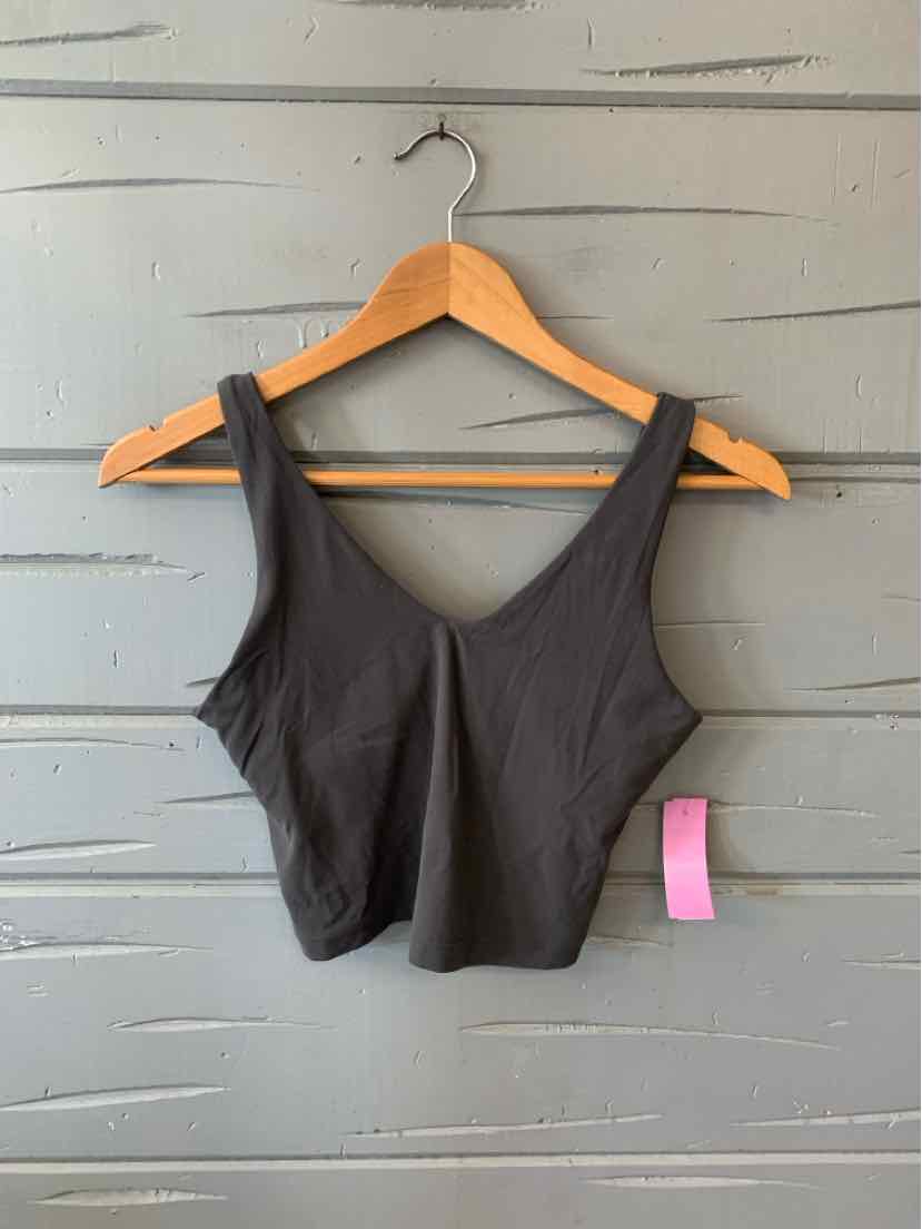Black sleeveless cropped athletic tank top with wide straps hanging on wooden hanger.