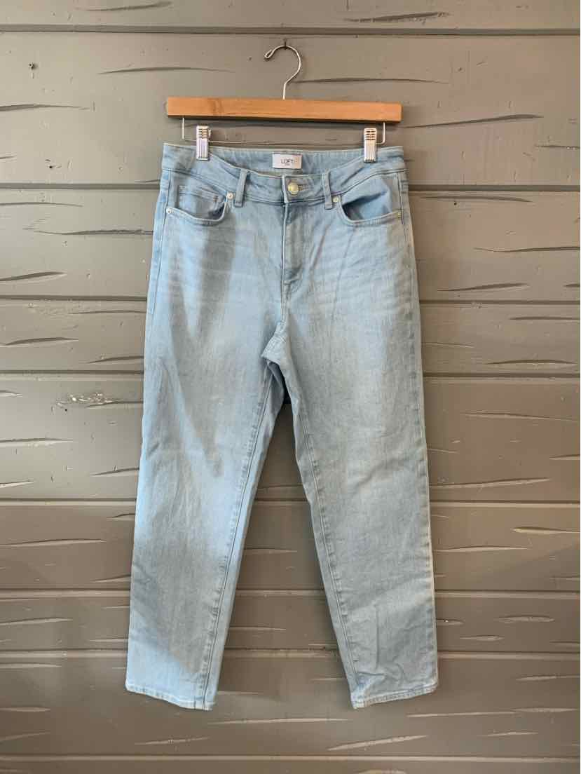 Light blue denim jeans with front and back pockets, straight-leg cut, and a high waist hanging on wooden hanger against.
