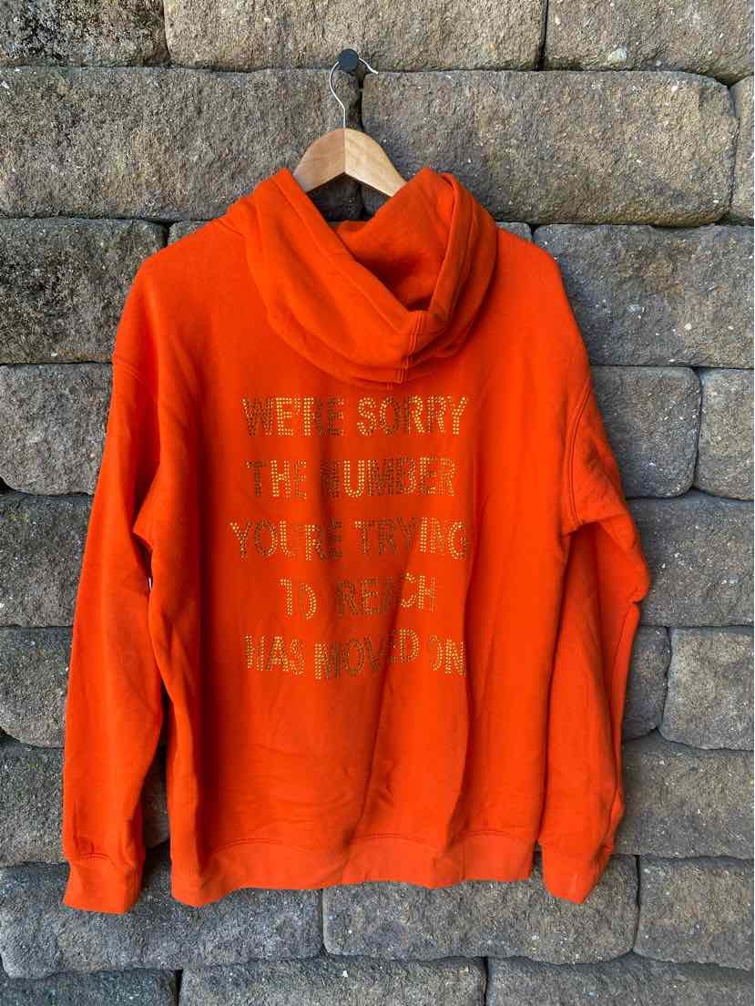 Bright orange hoodie with front kangaroo pocket and faded yellow text print across the chest.