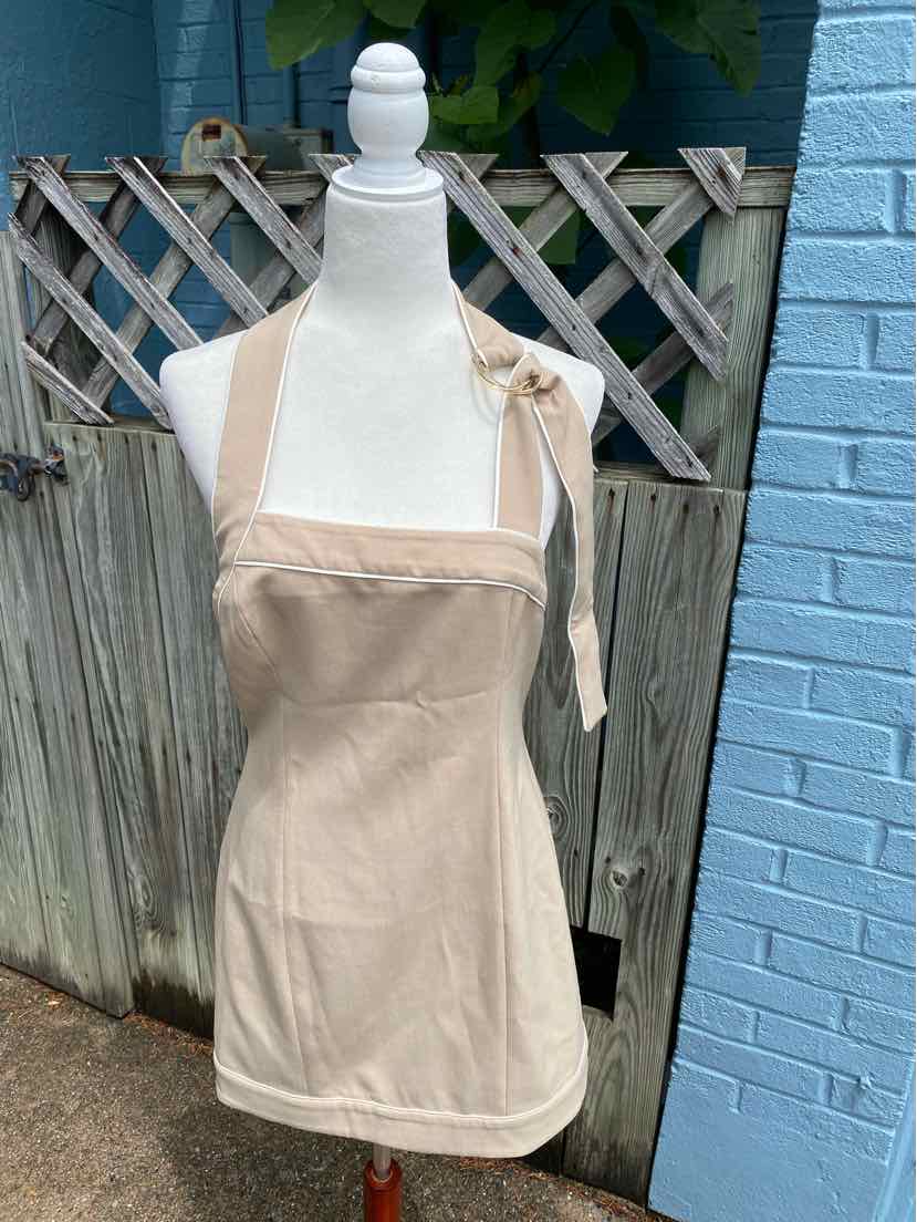 Tan sleeveless apron dress with square neckline and adjustable shoulder tie, fitted waist.