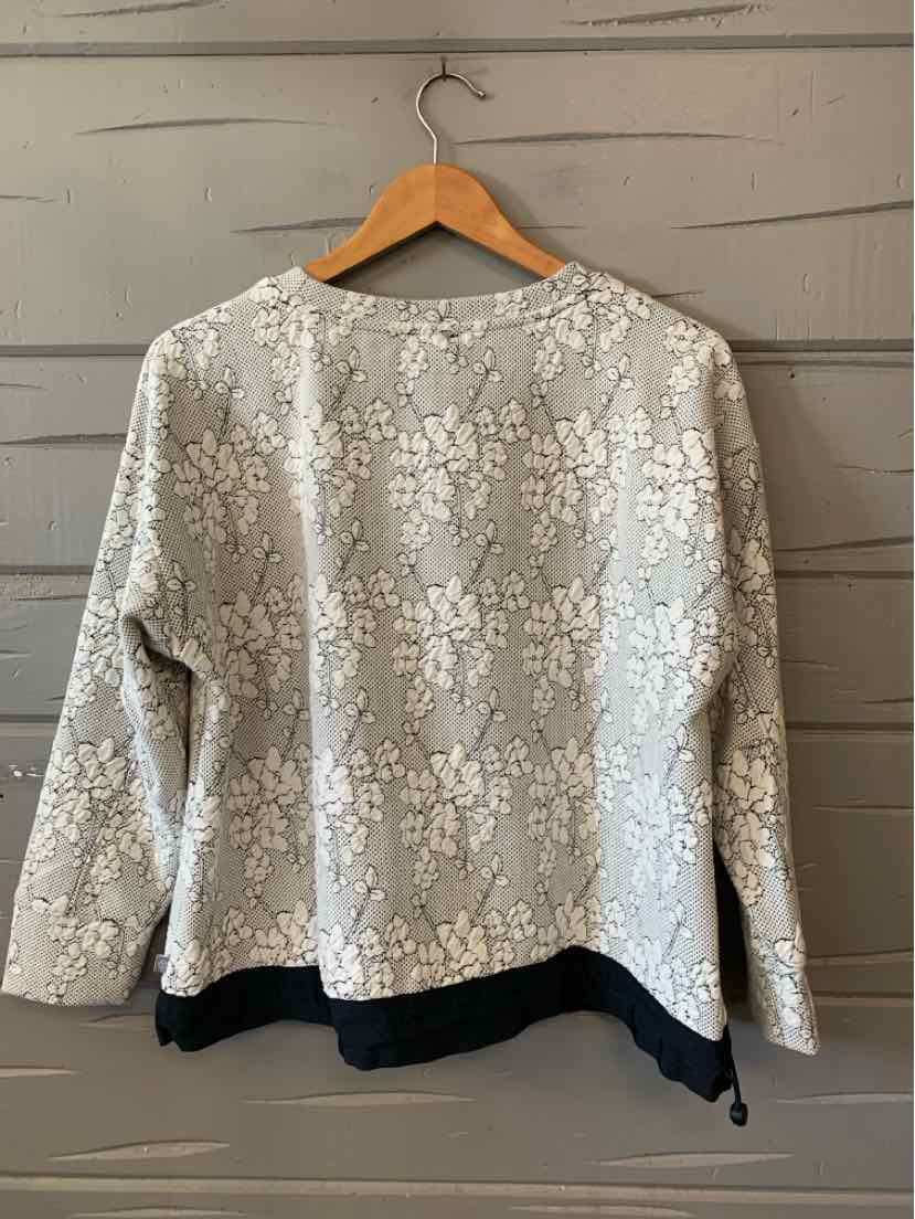 Light gray jacquard long-sleeve top with white floral pattern and black hem detail.