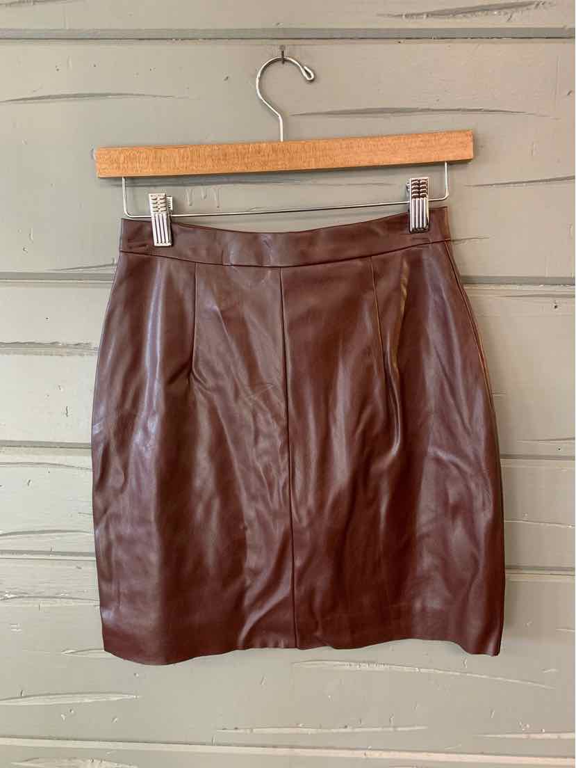 Burgundy faux leather mini skirt with seams and a fitted waistband on wooden hanger.