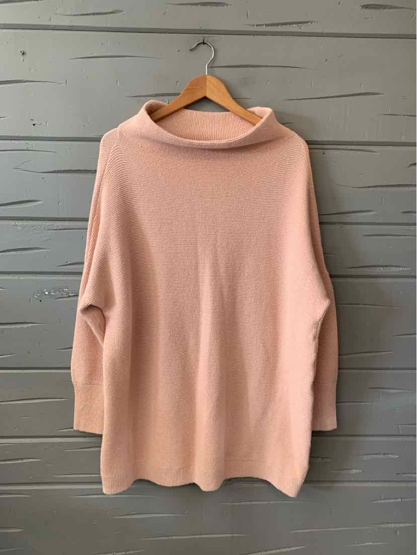 Soft blush pink oversized sweater with a wide cowl neck and long sleeves on a wooden hanger.