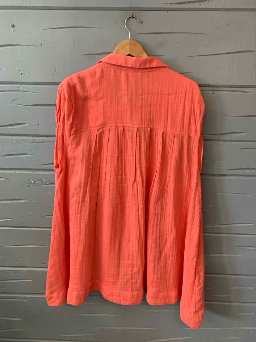 Coral long-sleeve blouse with soft, flowy fabric and back yoke pleats on wooden hanger.