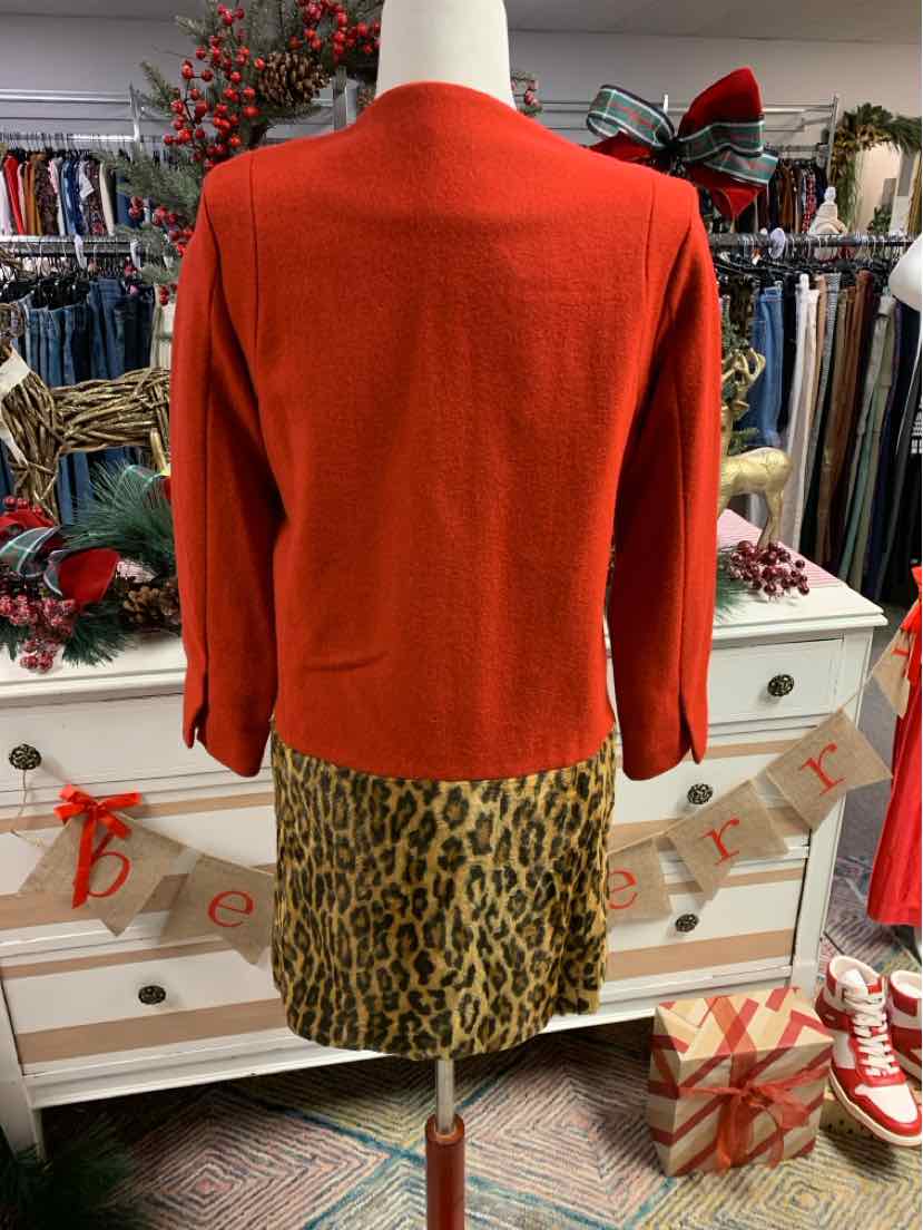 Orange long-sleeve sweater paired with leopard print skirt on mannequin in boutique setting.