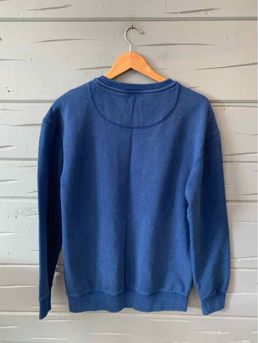 Navy blue long-sleeve sweatshirt with ribbed cuffs and hem, hanging on wooden hanger against white wooden wall.