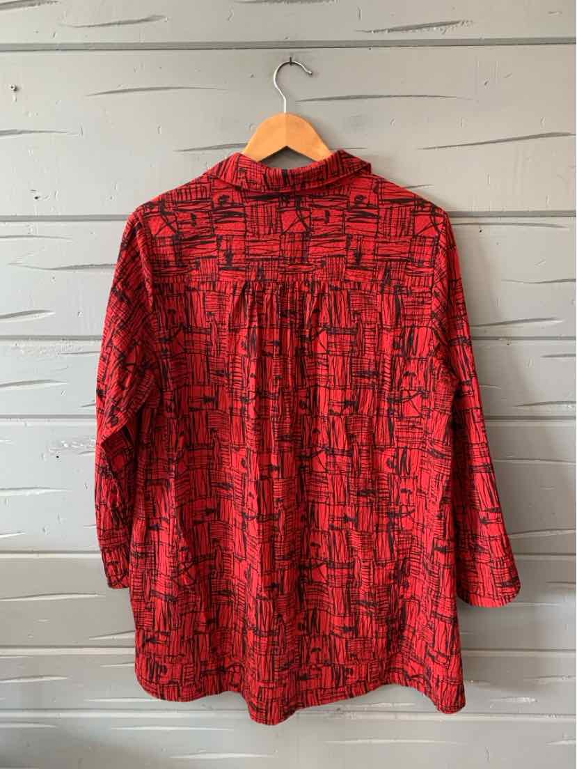 Red long-sleeve shirt with black geometric square pattern and relaxed fit hanging on wooden hanger.