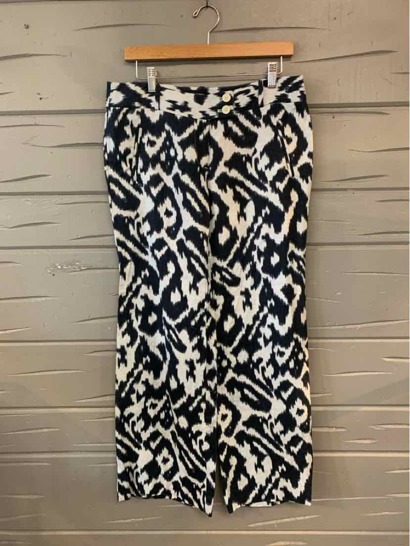 Black and white patterned wide-leg pants hanging on wooden hanger against gray wall.