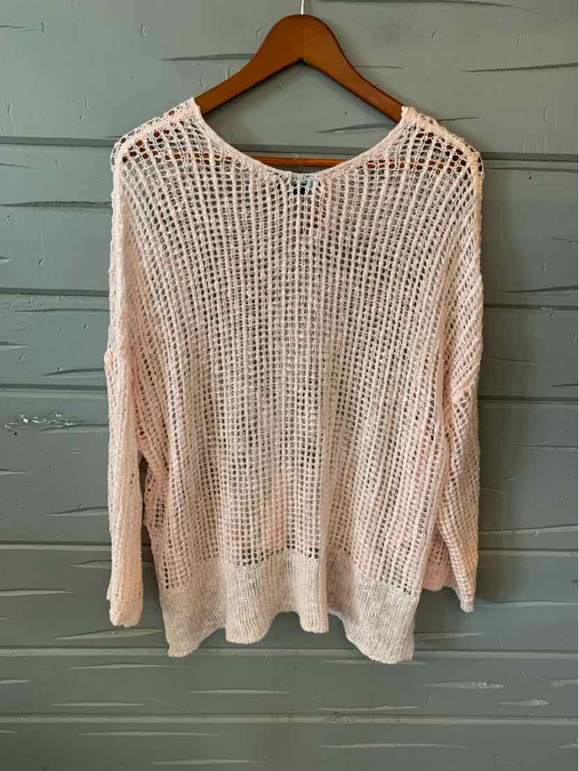 Light pink open-knit long sleeve sweater with a relaxed fit hanging on a wooden hanger.