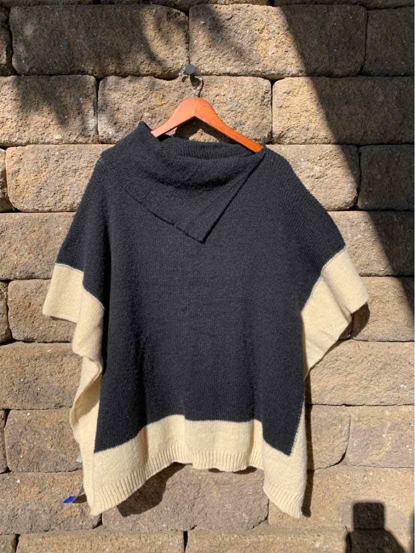 Black color-block short-sleeve knit top with cream panels at the sleeves and hem, displayed on a wooden hanger.