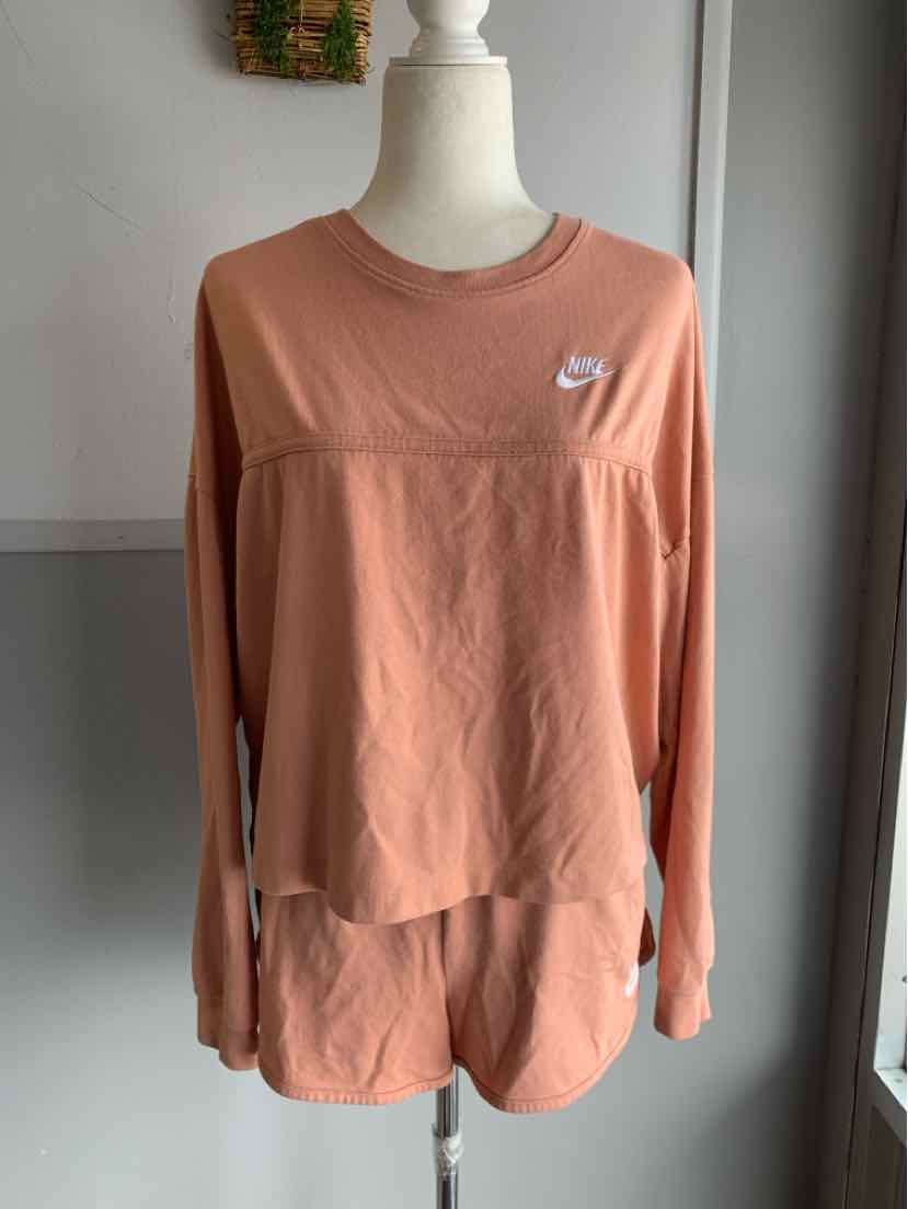 Light terracotta long-sleeve Nike shirt with white swoosh logo on chest, soft fabric, relaxed fit.