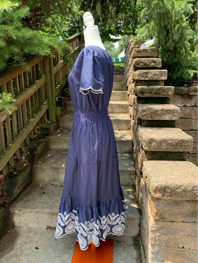 Navy blue sleeveless dress with cinched waist and white eyelet scalloped hem detailing.