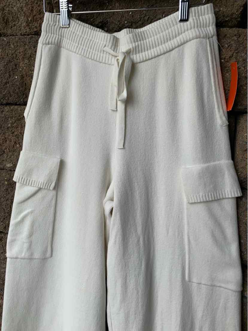 White knit shorts with ribbed elastic waistband and drawstring, featuring large cargo pockets on the sides.