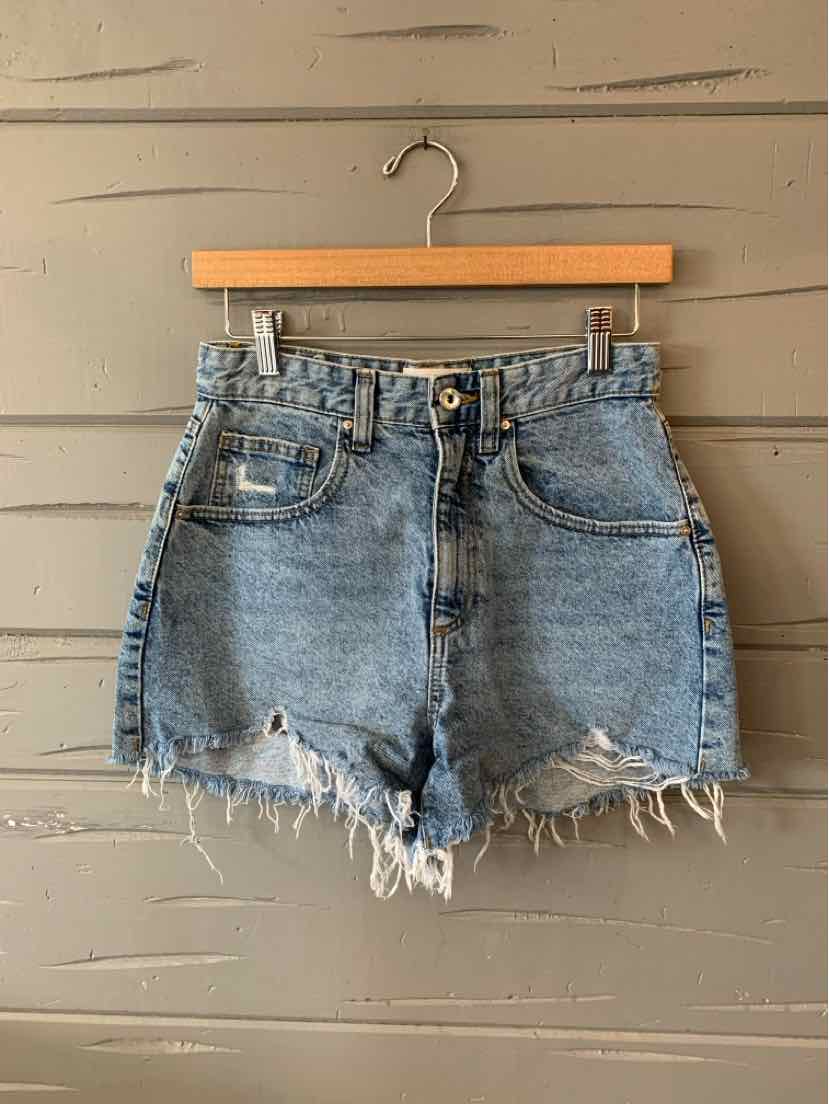 Light blue denim shorts with frayed hems and front pockets, hanging on wooden hanger.