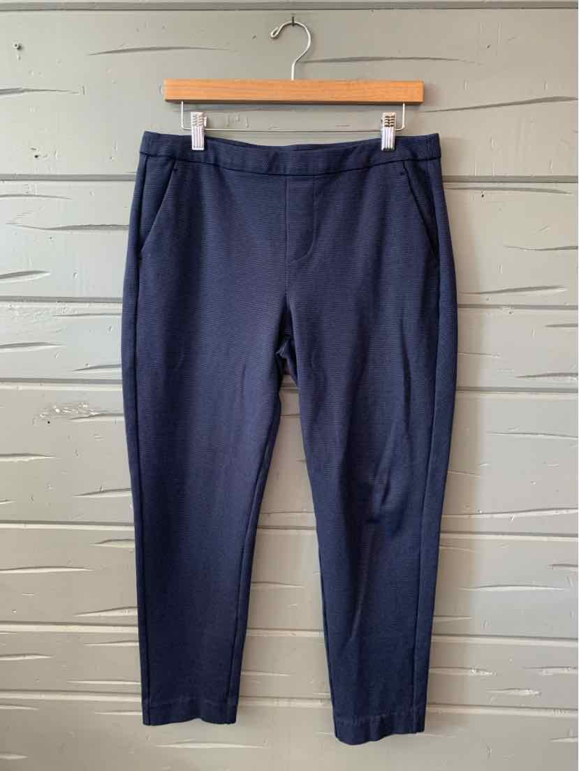 Navy blue women's tailored pants with flat front and ankle-length hem hanging on wooden hanger.