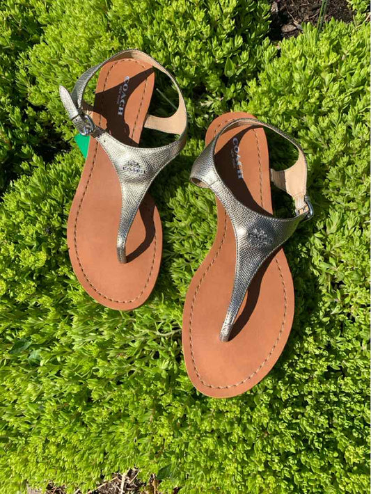 Woman's size 7.5 metallic silver Coach thong sandals with brown footbed and buckle strap.