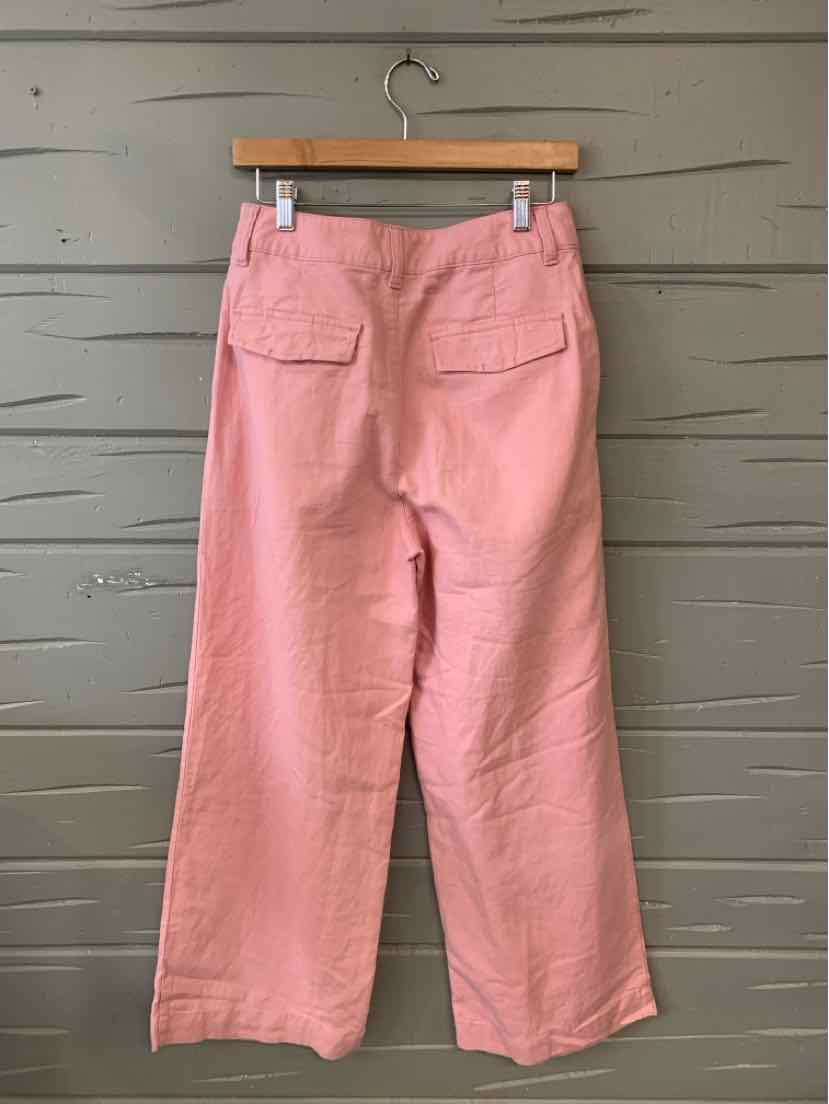 Pink wide-leg pants with back patch pockets and a high waist, hanging on wooden hanger.