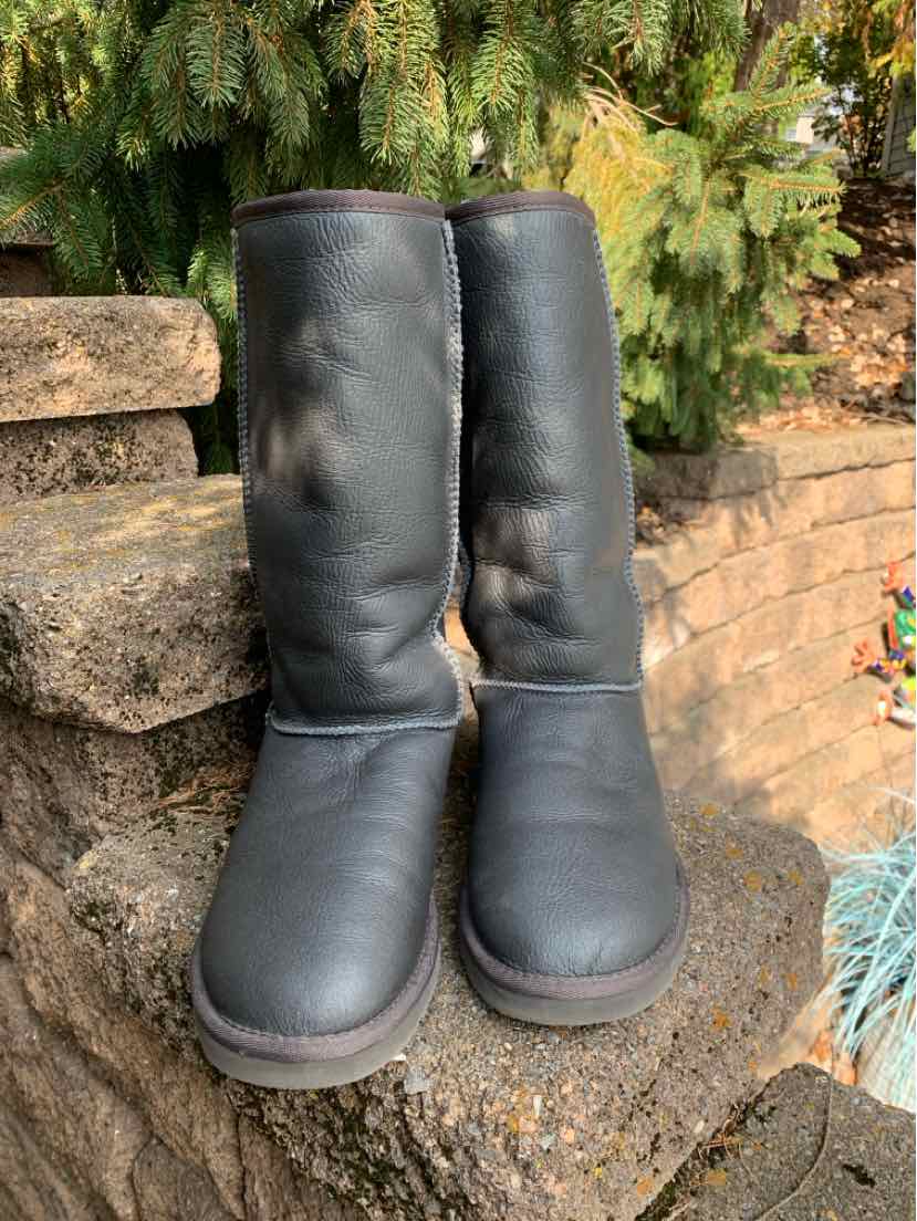Pair of dark gray UGG boots with soft suede uppers, rounded toes, and thick gray soles.