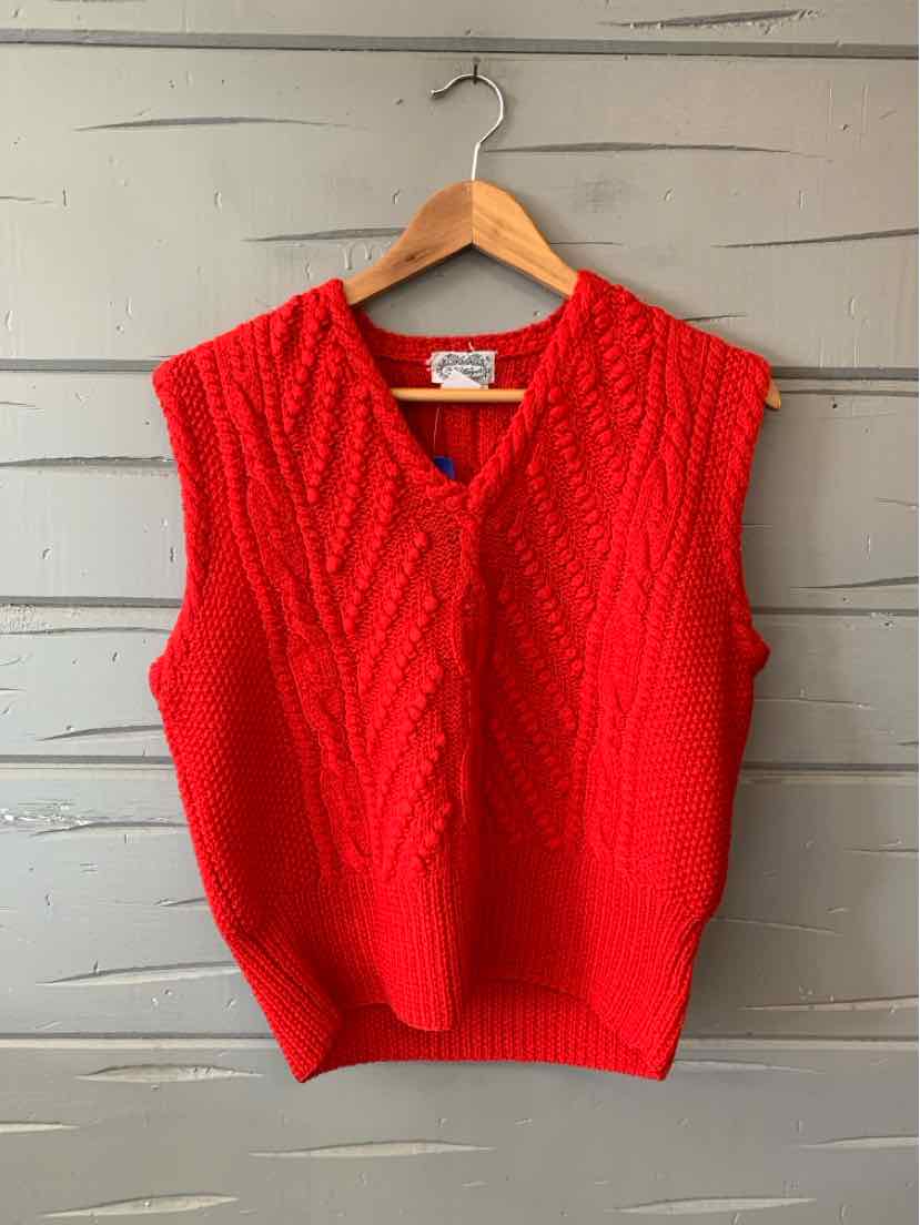 Bright red cable-knit women's sweater vest with a V-neck and ribbed hem, hanging on a wooden hanger.