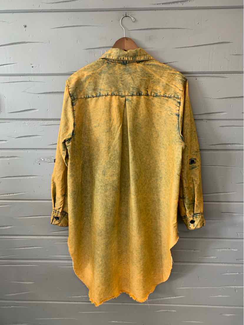 Long mustard yellow denim jacket with buttoned cuffs and a slightly curved hem hanging on a wooden hanger.