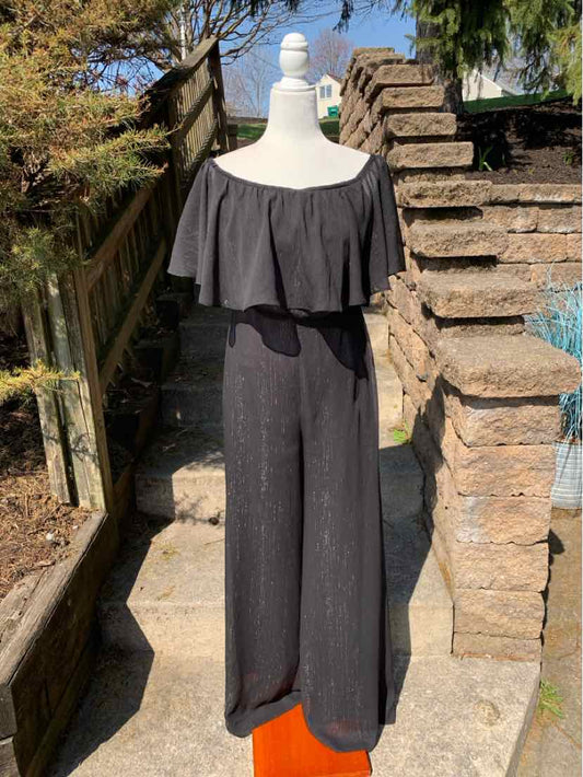 Black off-shoulder jumpsuit with ruffled neckline, wide-leg pants, size 6 on mannequin outdoors.