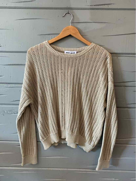 Tan ribbed knit long-sleeve sweater with crew neckline and relaxed fit on wooden hanger.