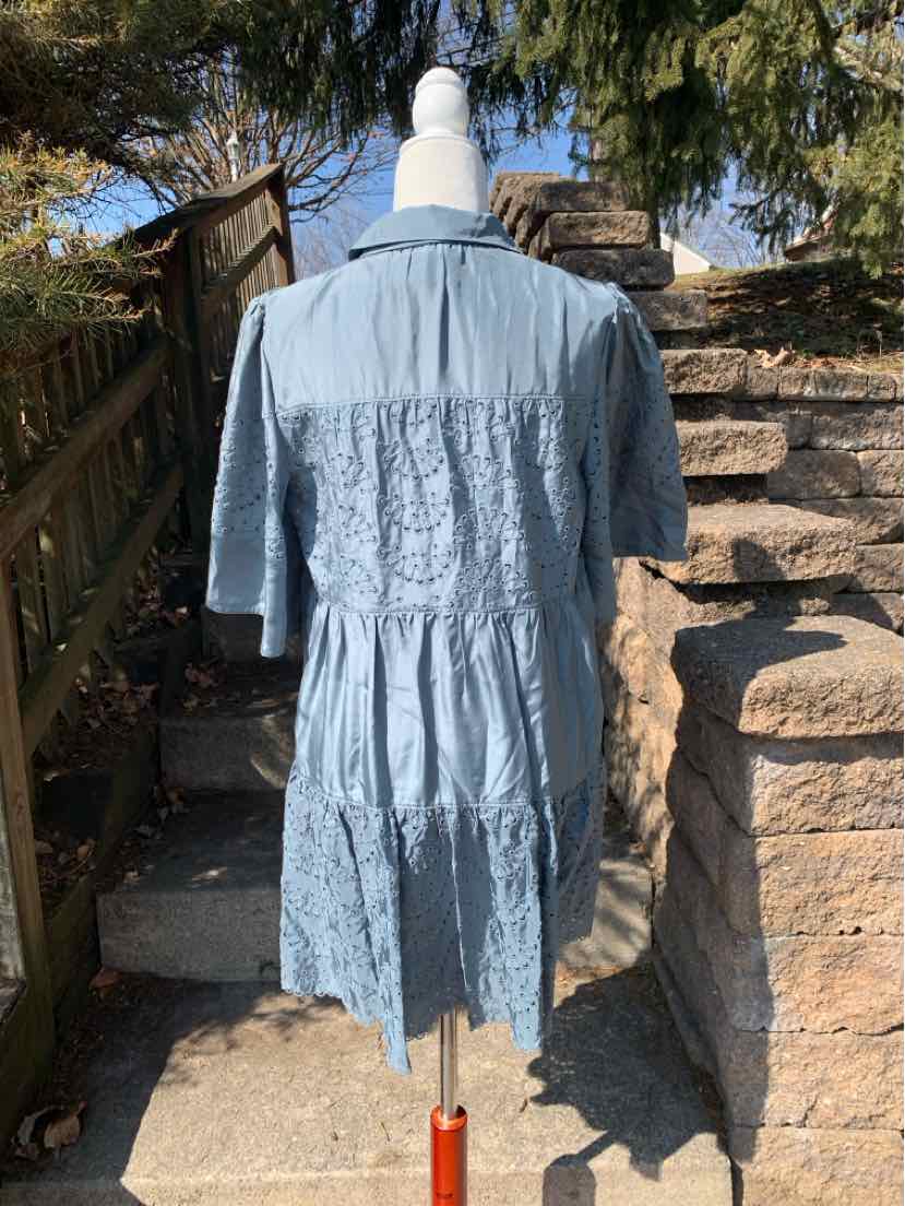 Blue eyelet dress with short sleeves and smocked back detail on mannequin outdoors.
