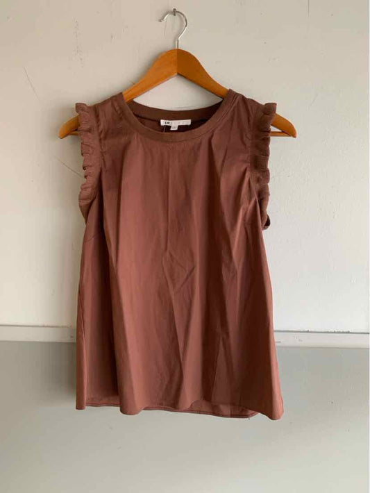 Sleeveless brown top with ruffled shoulder details on wooden hanger against white wall.