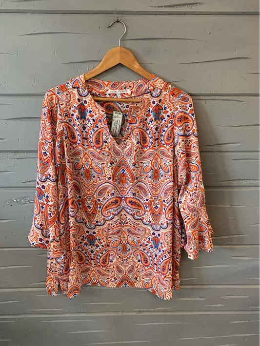 Long-sleeve paisley blouse in orange, purple, and white with gathered cuffs and a scoop neckline on a wooden hanger.