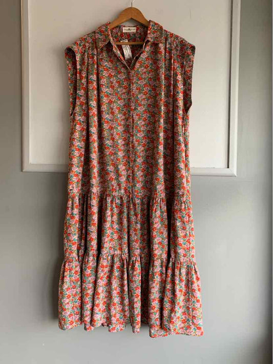 Sleeveless floral dress with orange, pink, and green flowers on a light background, tiered skirt, and collar neckline.