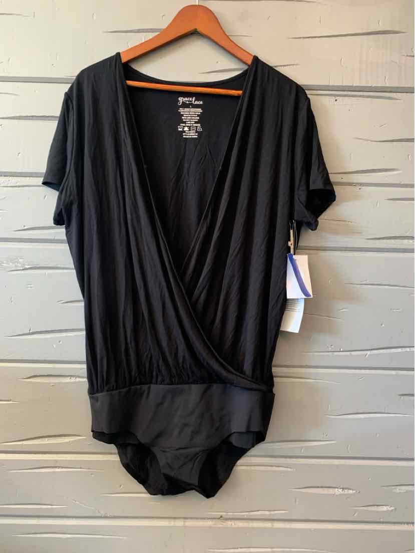 Black women's casual top with deep V-neck and wrap-front design hanging on wooden hanger.