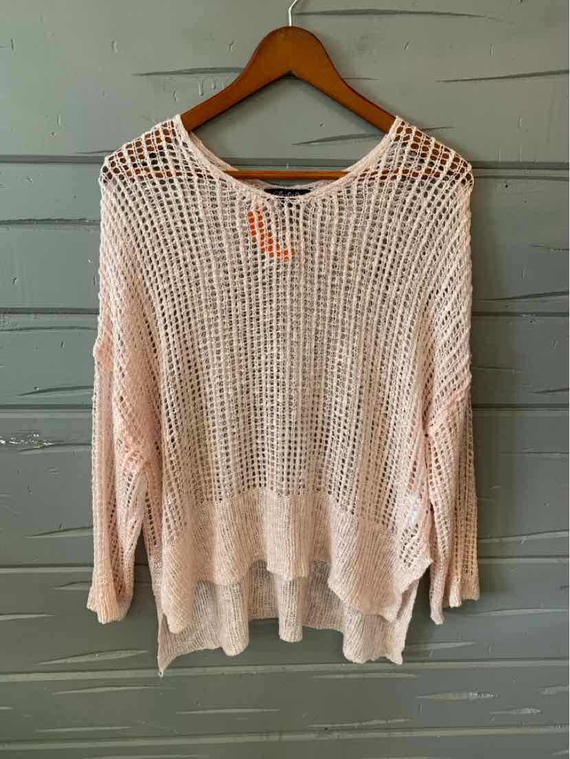 Light pink oversized knit sweater with loose open weave and long sleeves on wooden hanger.