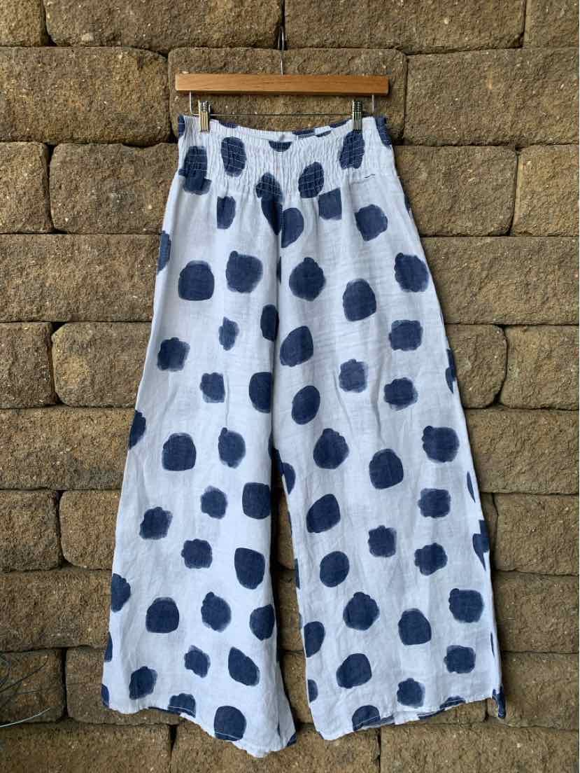 White wide-leg pants with large irregular black polka dots, lightweight fabric, elastic waistband.