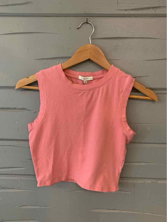 Sleeveless pink cropped tank top with round neckline on wooden hanger against gray wooden background.
