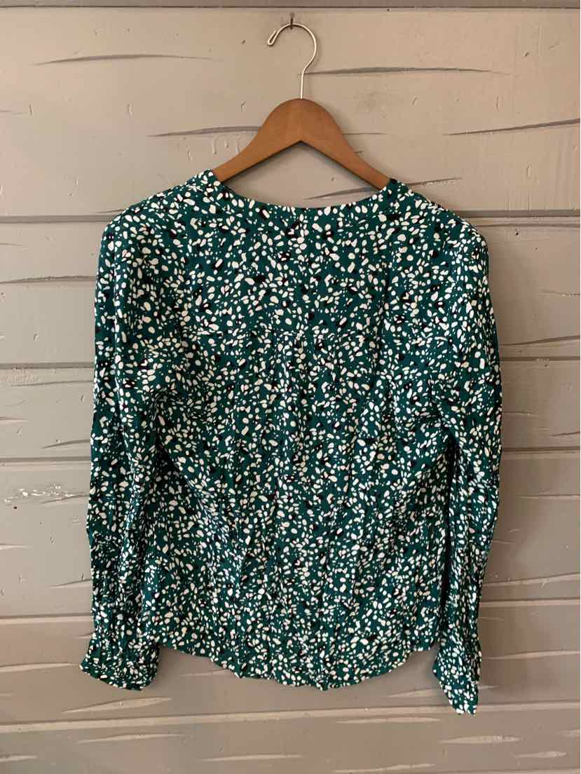 Green blouse with white and black floral pattern, long sleeves, and round neckline.