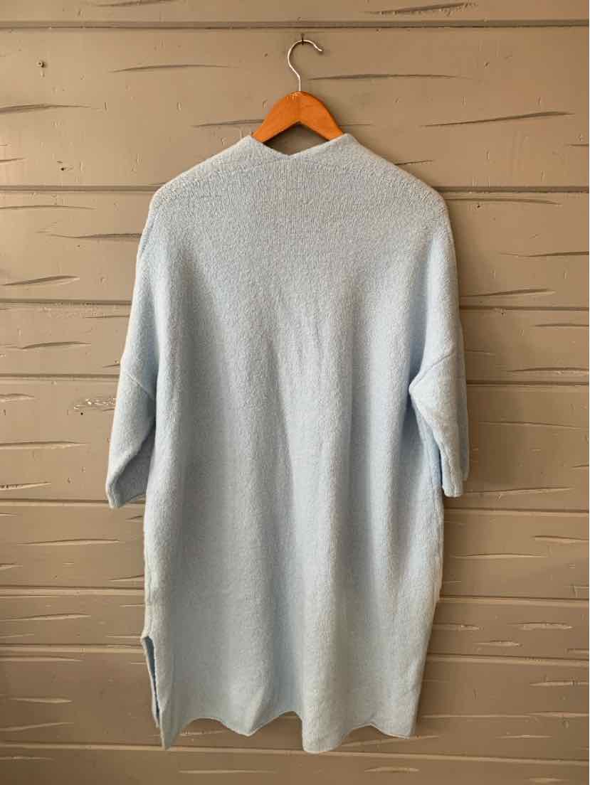 Light blue soft knit sweater dress with three-quarter sleeves and side slits on wooden hanger.