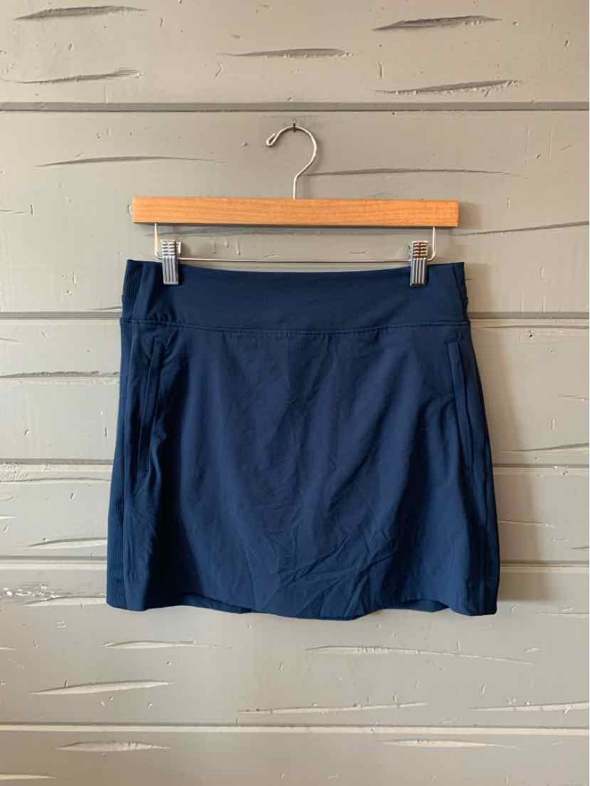 Navy blue mini skirt with wide waistband, lightweight fabric, and slight flare hem hanging on wooden hanger.