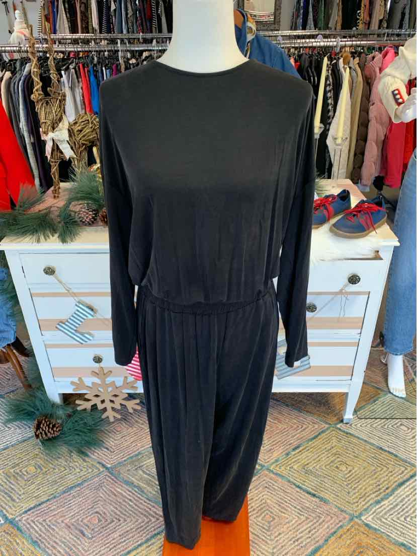 Black long-sleeve jumpsuit with cinched waist and relaxed fit on mannequin.