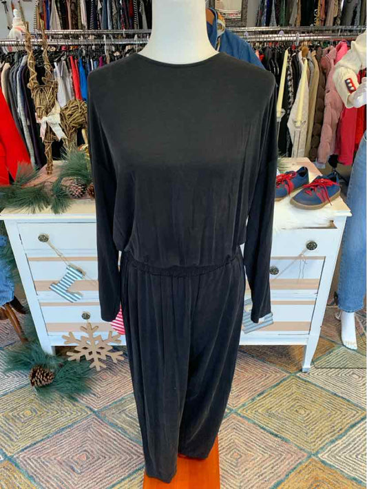 Black long-sleeve jumpsuit with cinched waist and relaxed fit on mannequin.