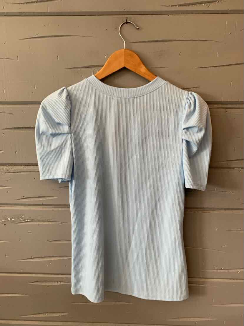 Light blue short-sleeve top with puffed sleeves and crew neckline hanging on wooden hanger.