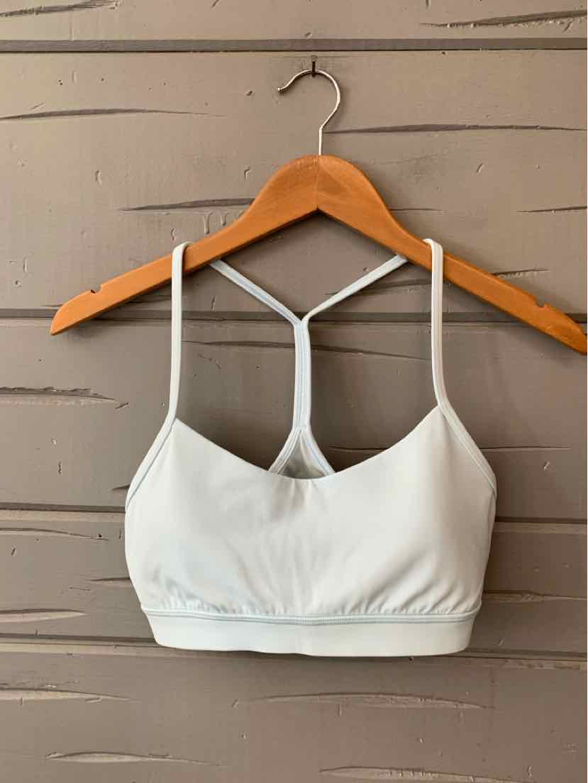 White Lululemon sports bra with thin straps and a T-back design on a wooden hanger.