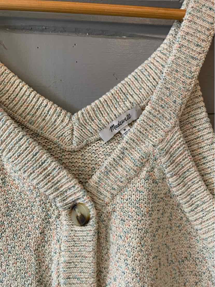 Close-up of a multi-colored knit cardigan with ribbed collar and button detail.