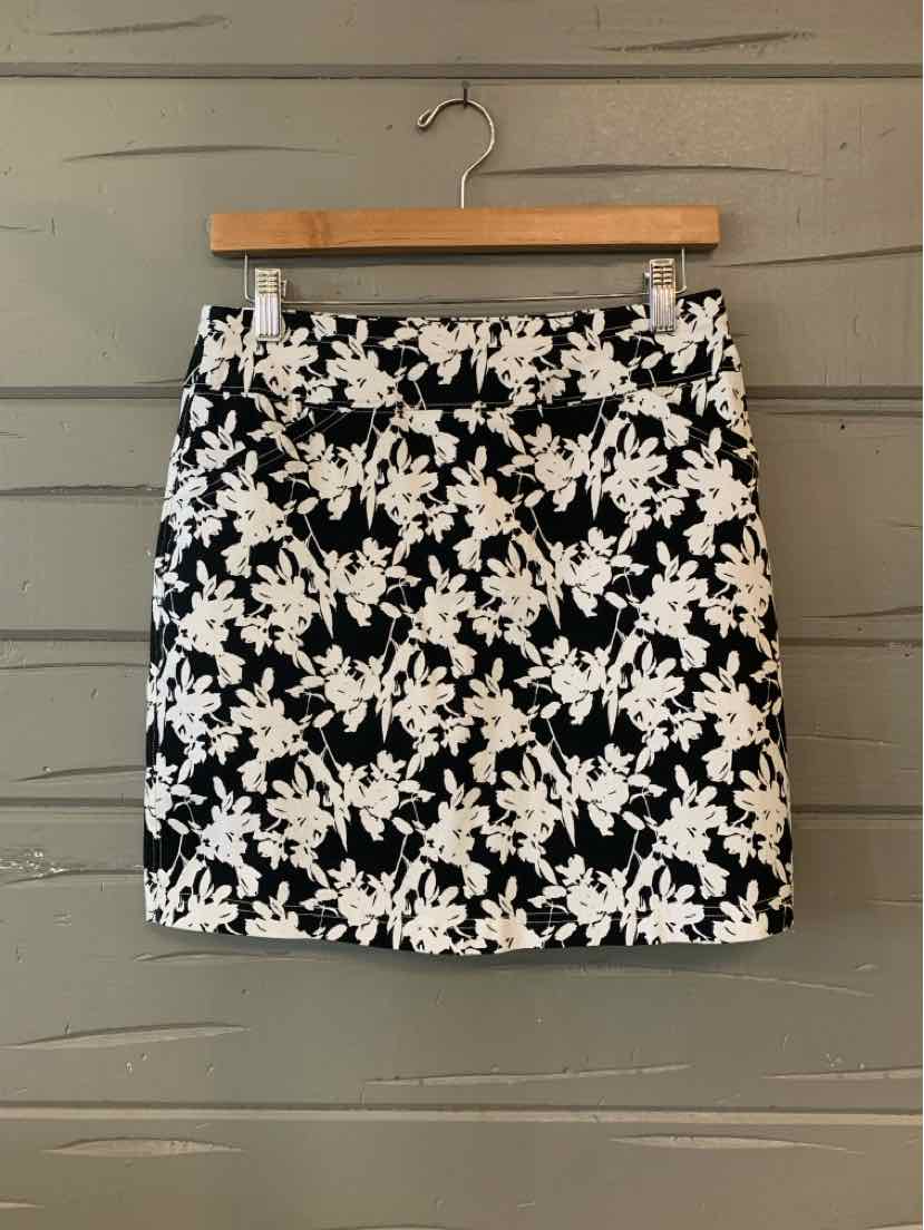 Black and white floral mini skirt with front pockets and belt loops on wooden hanger.