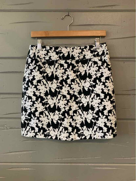 Black and white floral mini skirt with front pockets and belt loops on wooden hanger.