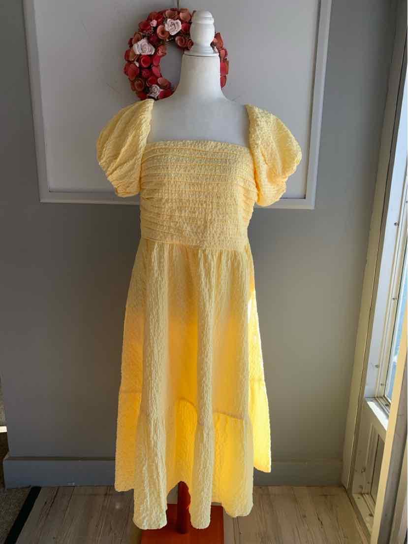 Yellow midi dress with puff sleeves and smocked bodice on white mannequin.